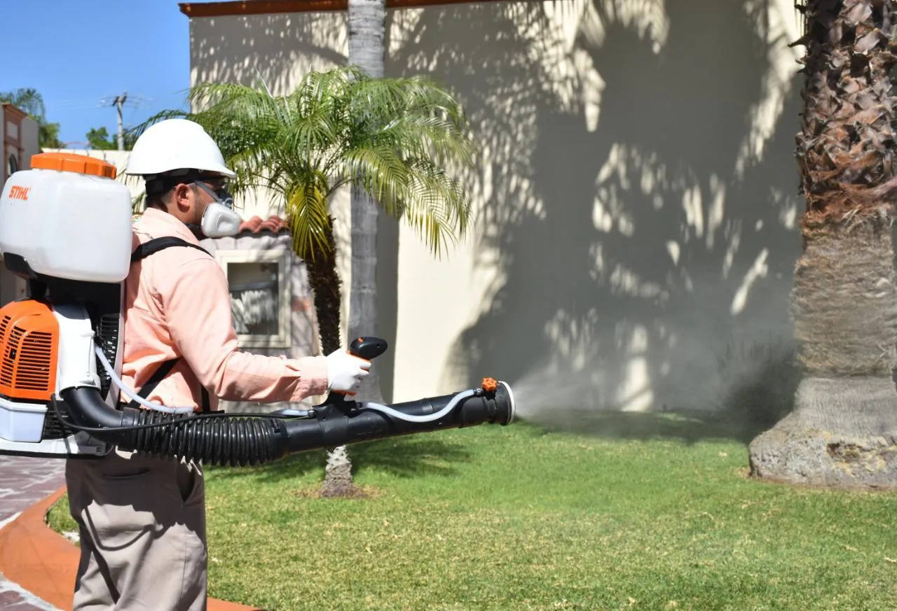 Técnico de Ozetta aplicando aspersión con motomochila en el jardín de una casa en León